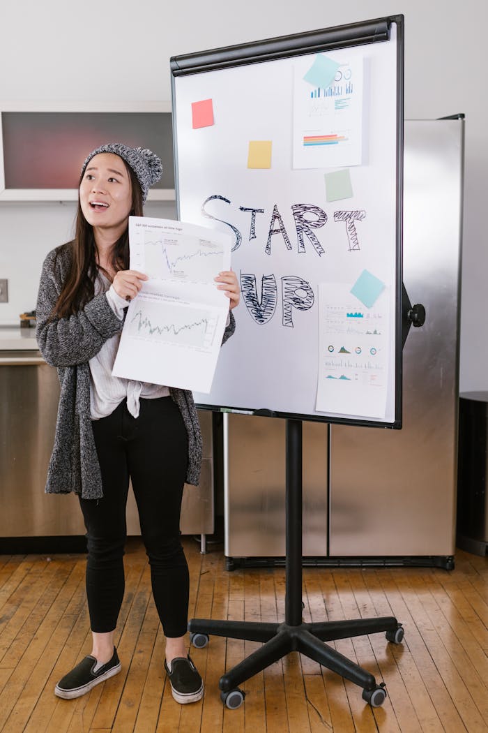 services-04 A young woman gives a startup presentation with charts and graphs on a flipchart.